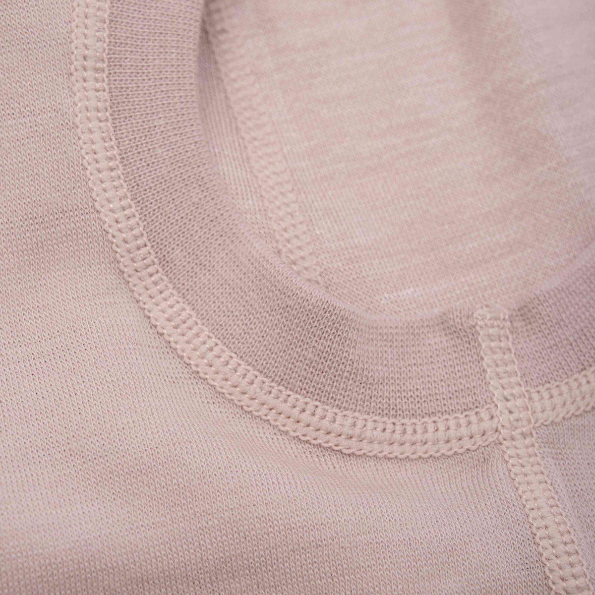 Nahaufnahme der hellrosa CeLaVi – Balaclava aus 100 % Merinowolle mit detaillierten Nähten am Halsausschnitt und an den Säumen. Der Stoff wirkt weich und fein gewebt, was die Handwerkskunst der Näharbeit unterstreicht. Dieses Stück ist außerdem nach OEKO-TEX® STANDARD 100 zertifiziert, was für zusätzliche Sicherheit sorgt.